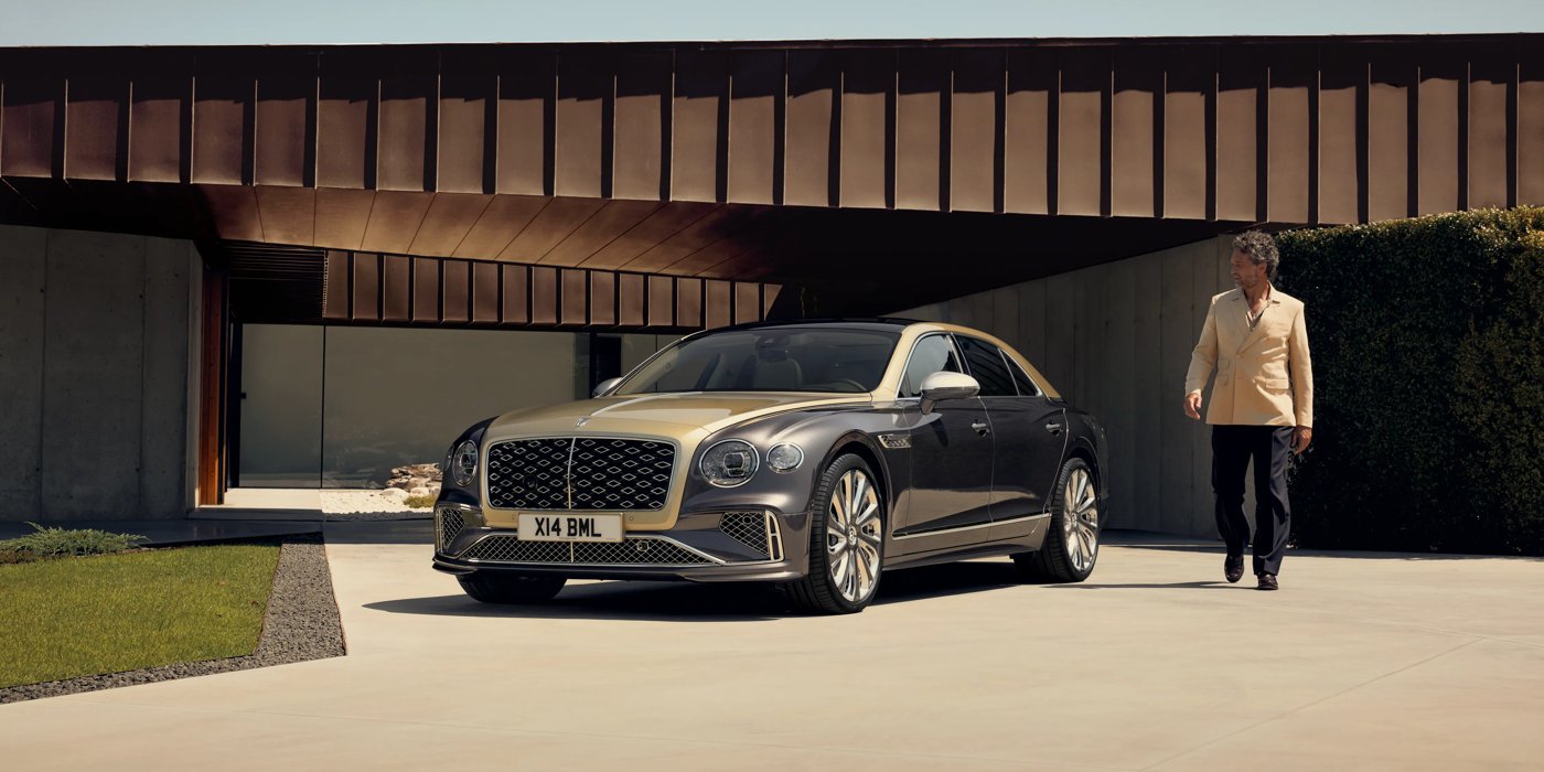 Bentley Jakarta Bentley New Flying Spur Mulliner V8 hybrid sedan front three quarters in Rose Gold over Magnetic paint, parked near modern home