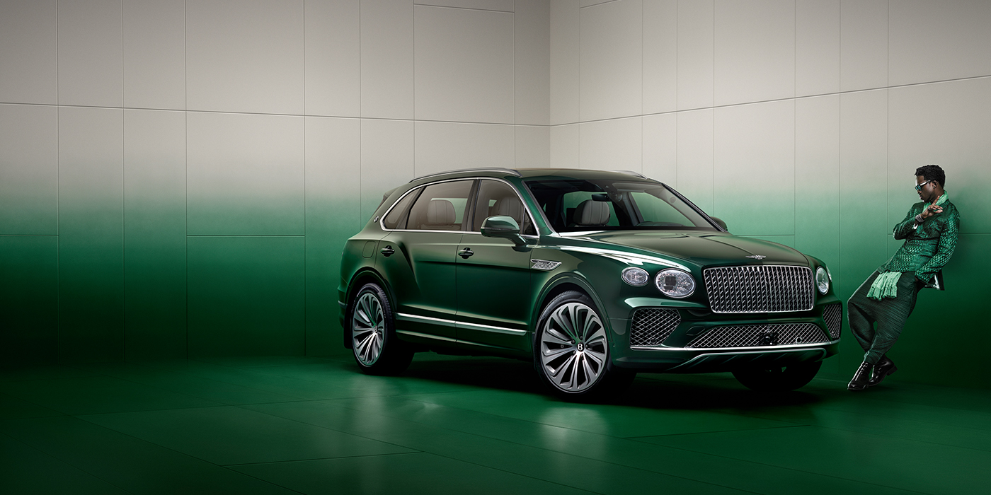 Bentley Jakarta Wisdom K leans against wall next to Bentley Bentayga Extended Wheelbase Atelier Edition SUV in Light Emerald green paint