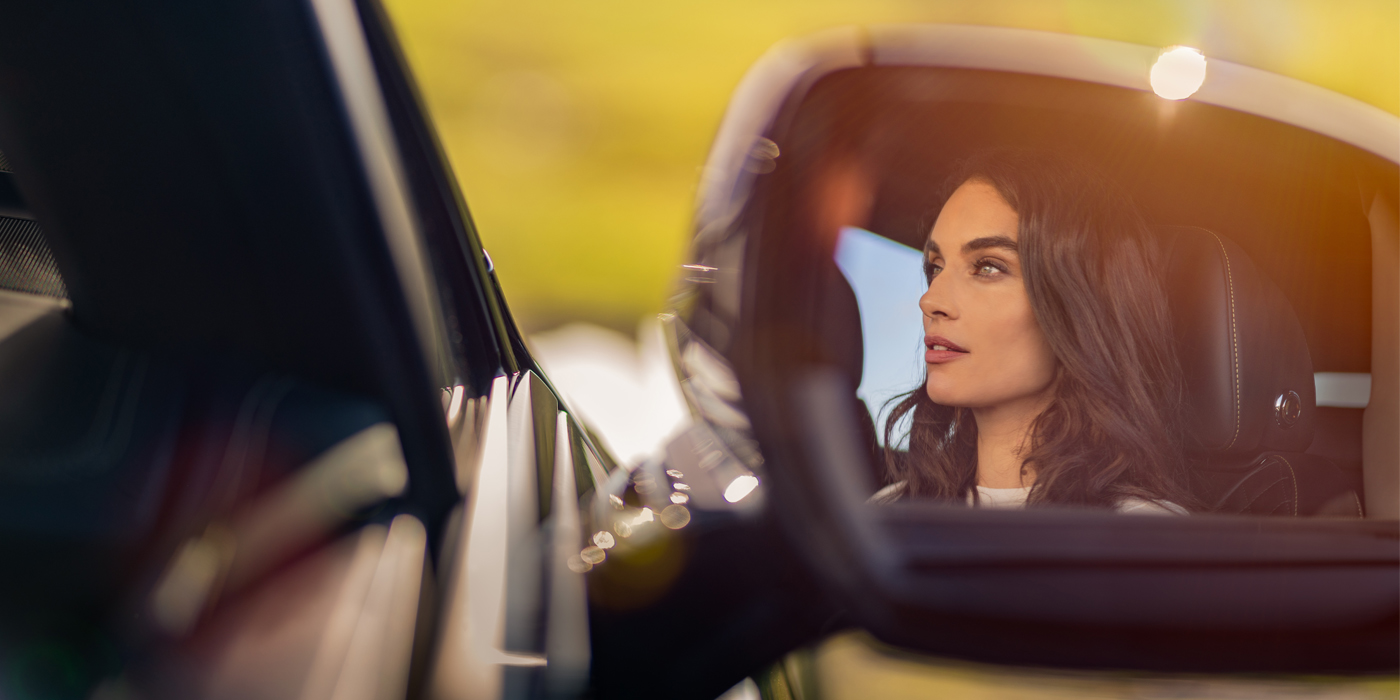 Bentley Jakarta profile of dark haired woman's face in mirror of Bentley car in sunlight