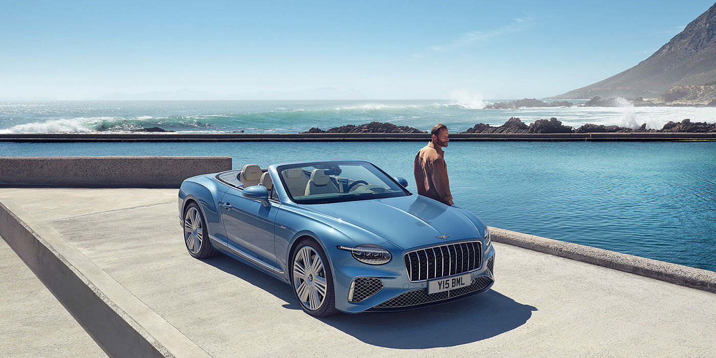 Bentley Jakarta New Bentley Continental GTC Azure convertible front view in Light Windsor blue paint with 22 inch ten spoke wheels parked by the sea in the sunshine