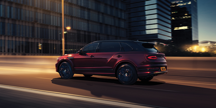 Bentley Jakarta Bentley Bentayga Extended Wheelbase Mulliner SUV in Cricket Ball red paint driving dynamically in city at night